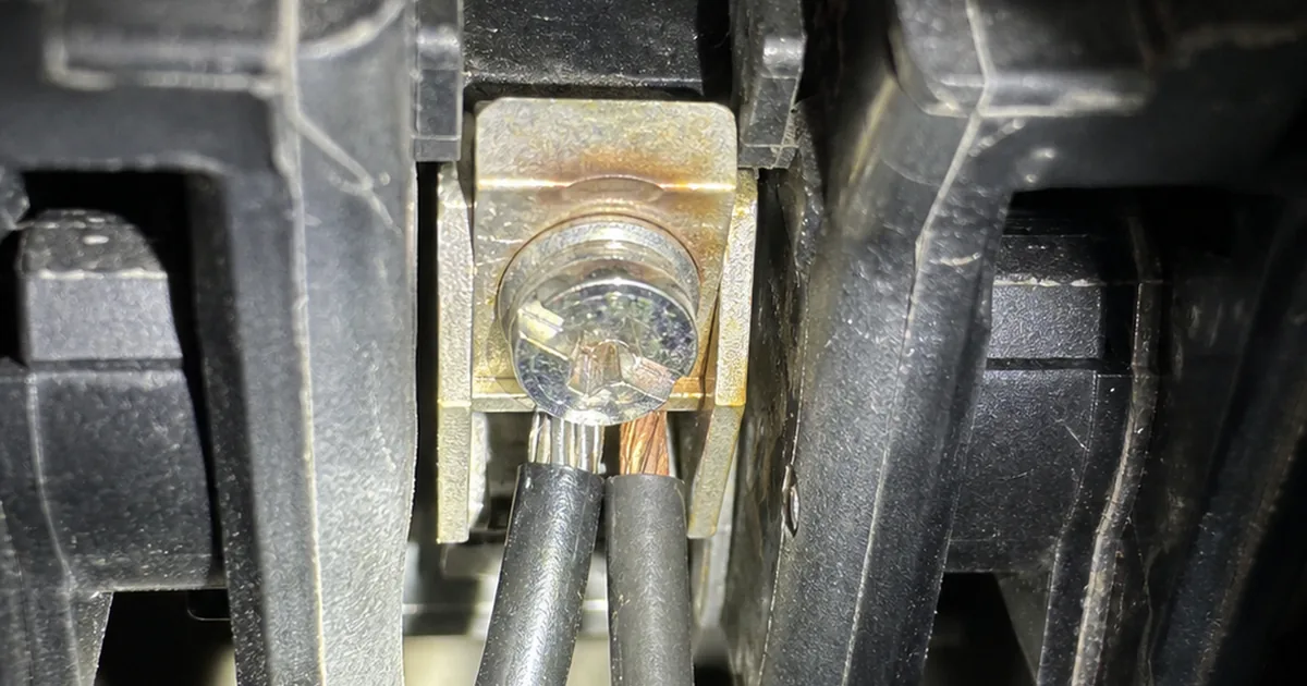An open electrical panel in a Cerritos home with a breaker removed to show two black conductors landed under a single lug designed for one