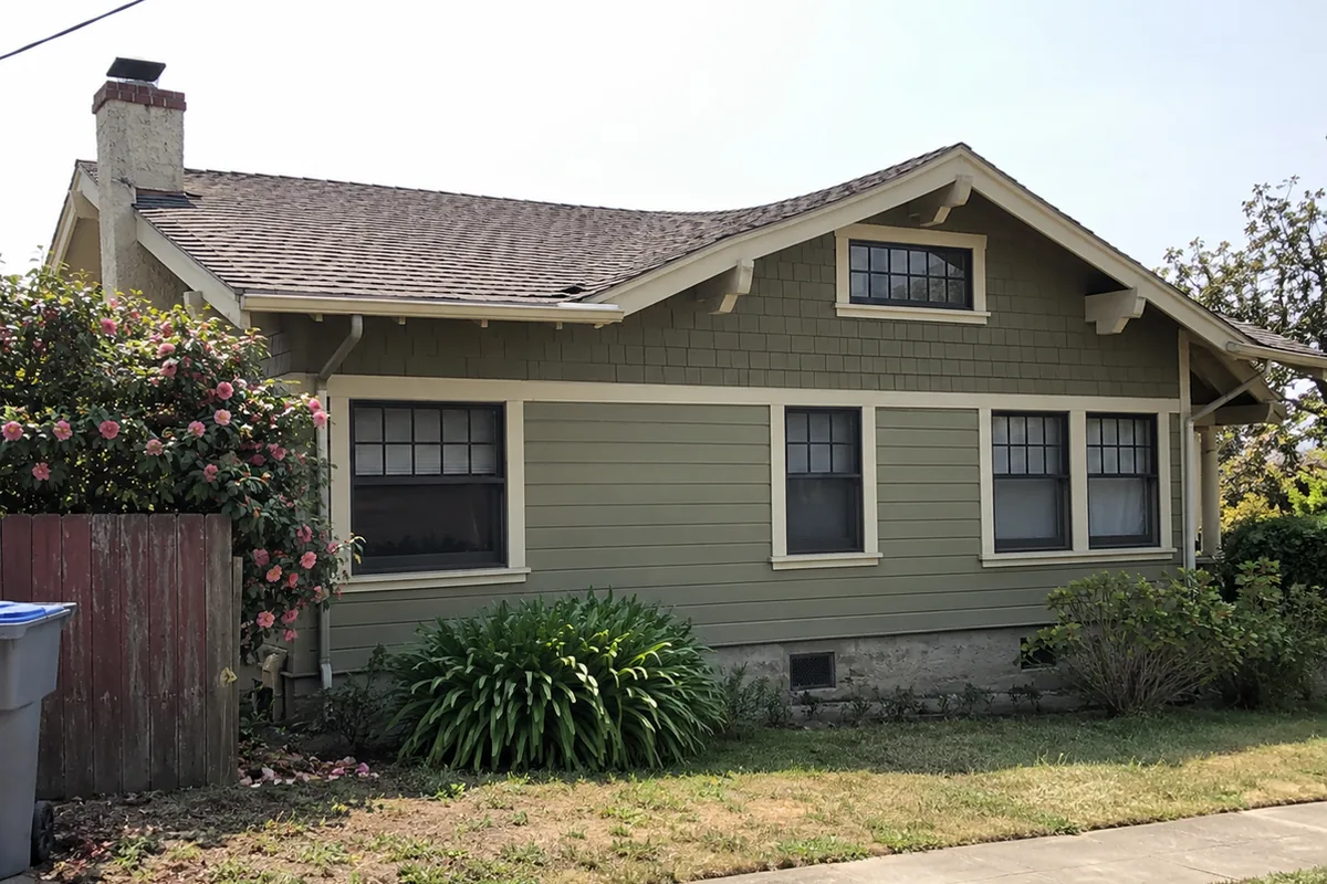 Craftsman-era bungalow seen from the side with the roof line dipping in the middle between the chimney and the front gable