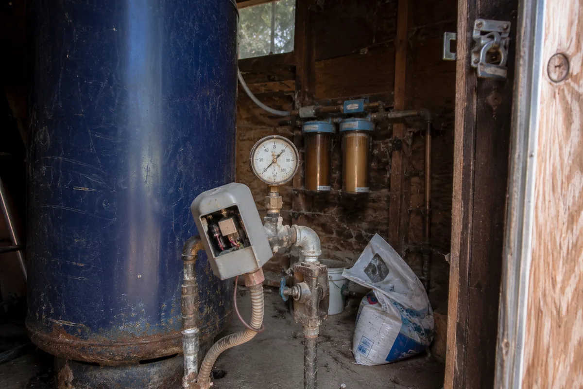 Well pressure tank, gauge, and filtration equipment inside a Fallbrook pump house