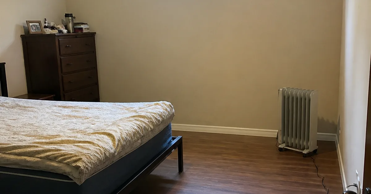 A converted room in a Fremont home with a small high window, no closet, and a portable space heater standing in the corner where a permanent heat source should be