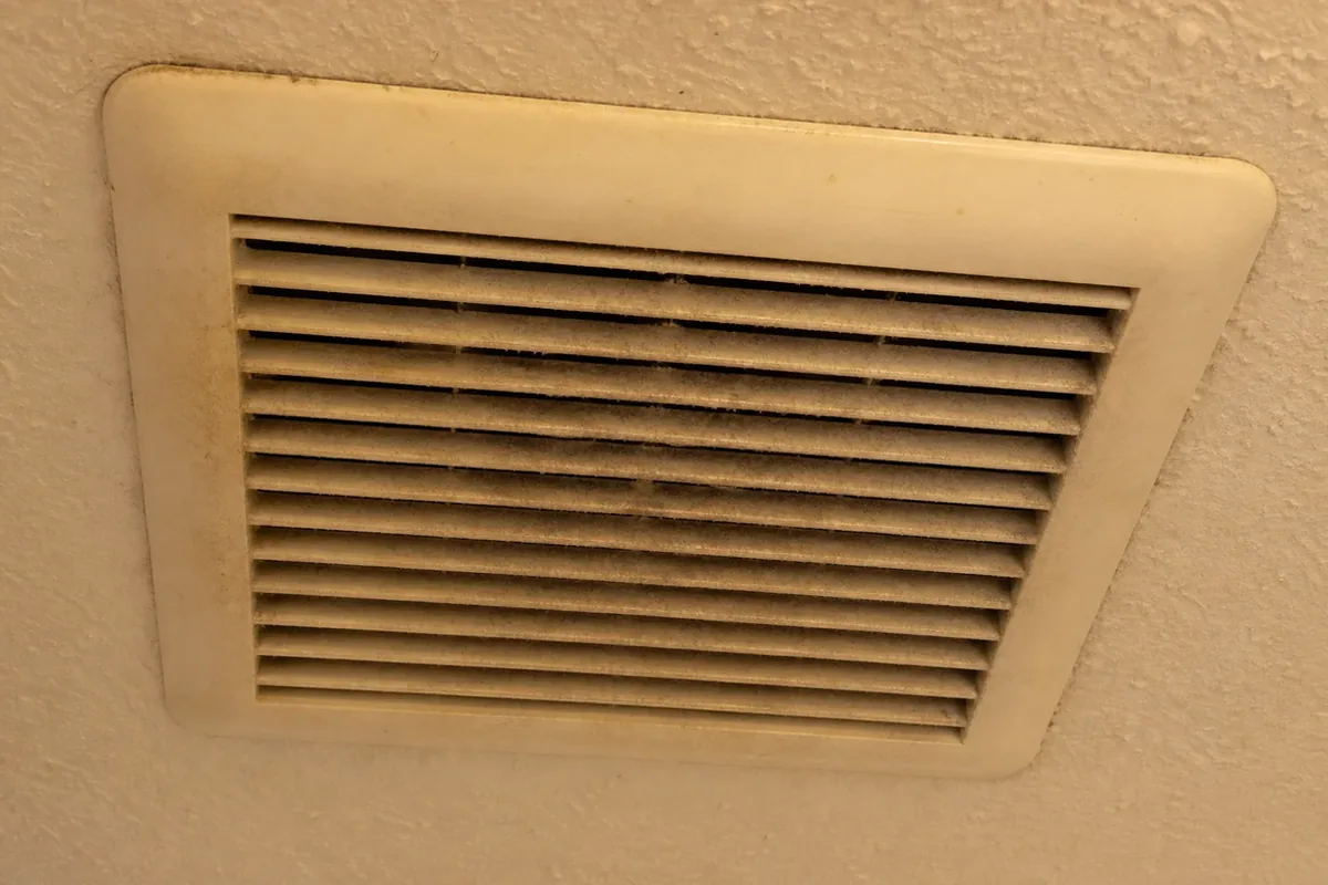 A bathroom ceiling and exhaust fan grille in a National City home shown in available window light, no visible ventilation duct routing to the exterior