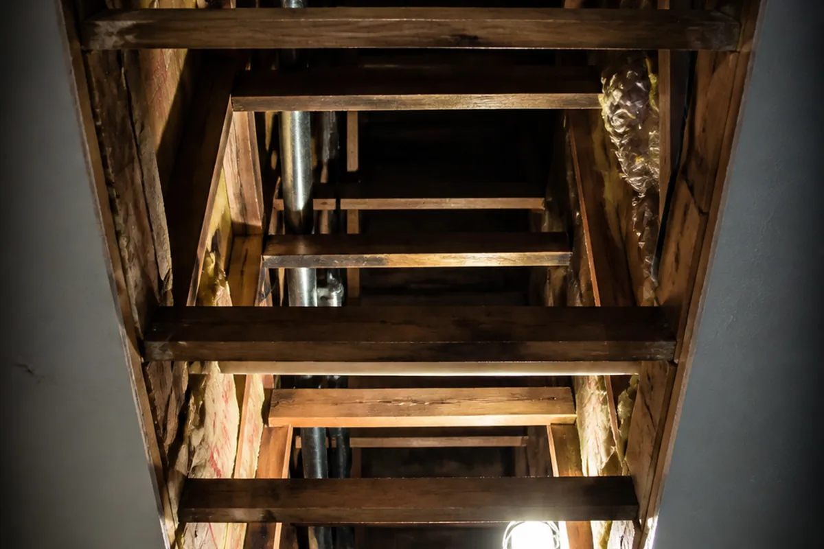 Straight-up view into an open ceiling cavity above a Paramount garage conversion, showing an unblocked path between the converted space and the attic above