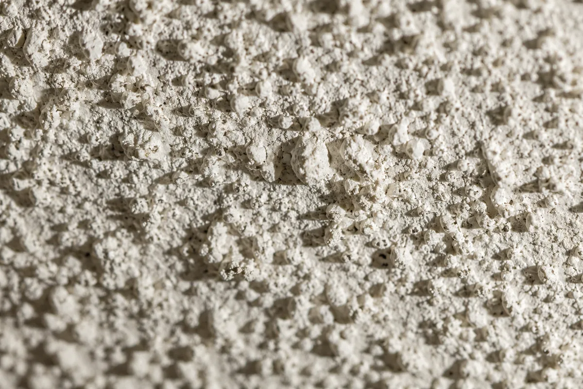 Close-up of a textured popcorn acoustic ceiling in a mid-century home, the kind of sprayed finish that can contain asbestos in pre-1980 homes