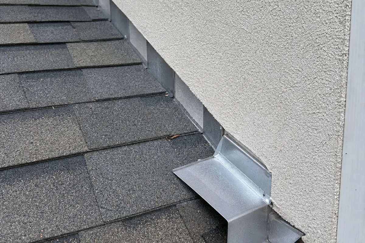 A properly installed kick-out diverter at the bottom of a step-flashing run, the bent metal piece extending outward over the gutter