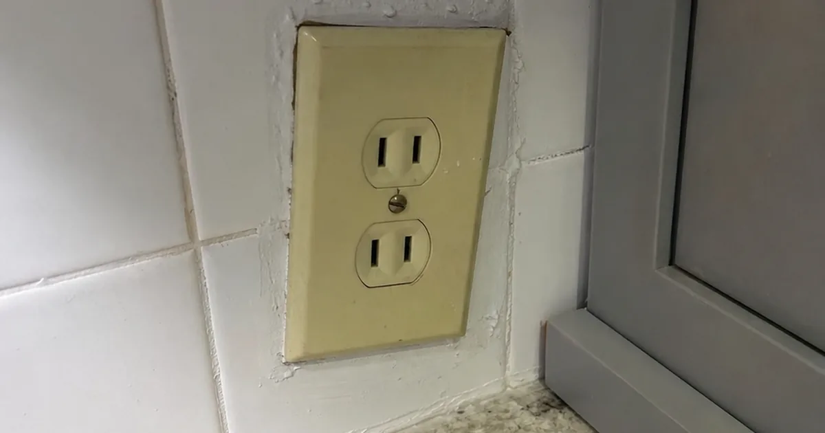 An old two-prong outlet in a Redlands kitchen with no ground and no GFCI protection