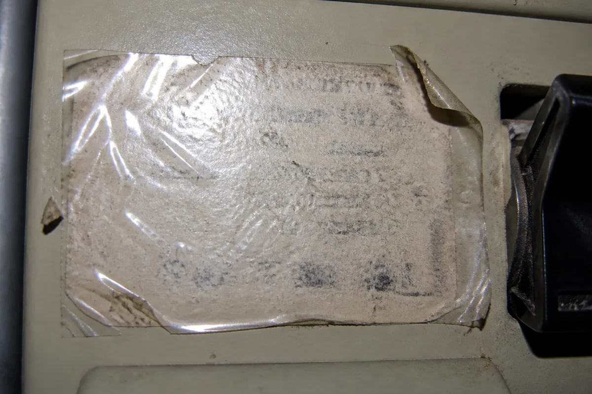 Close macro view of a faded, illegible handwritten label at an electrical disconnect switch, the text no longer readable