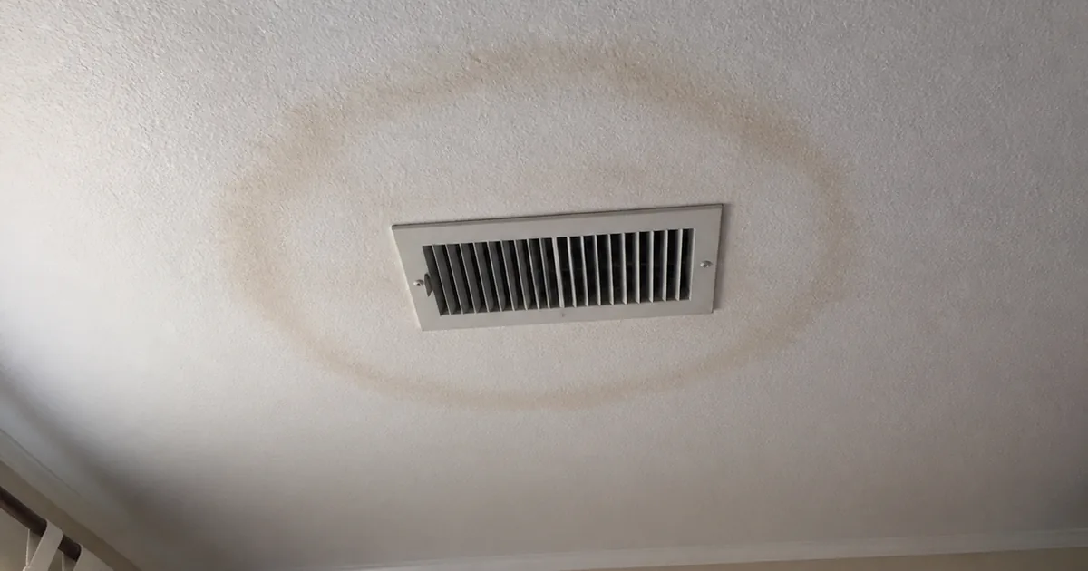 A ceiling-mounted HVAC register in a Solana Beach home with a soft brown staining ring on the drywall around it