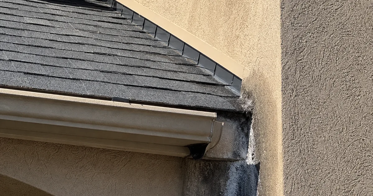 A roof-to-wall junction on a Whittier stucco home where the step flashing terminates at the gutter with no kick-out diverter installed