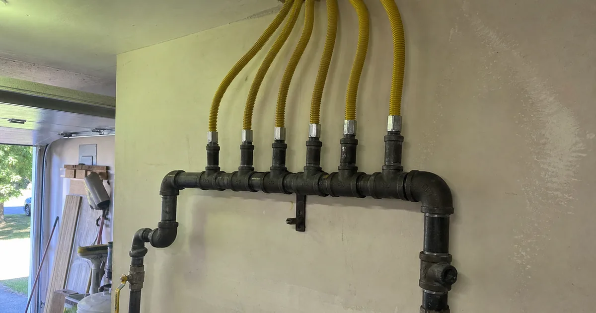 Yellow CSST flexible gas line at a manifold in a Yorba Linda garage with no bonding clamp visible