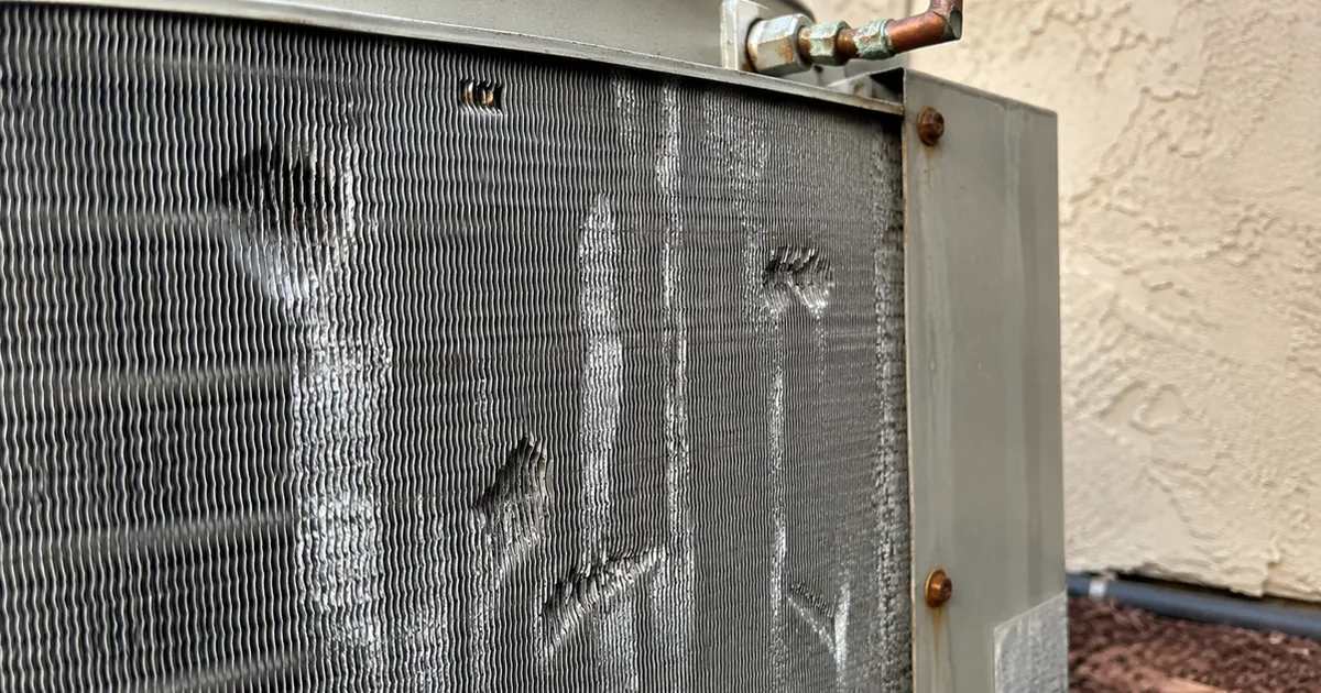 Pitted aluminum AC condenser fins showing salt air corrosion damage at a coastal Carlsbad home