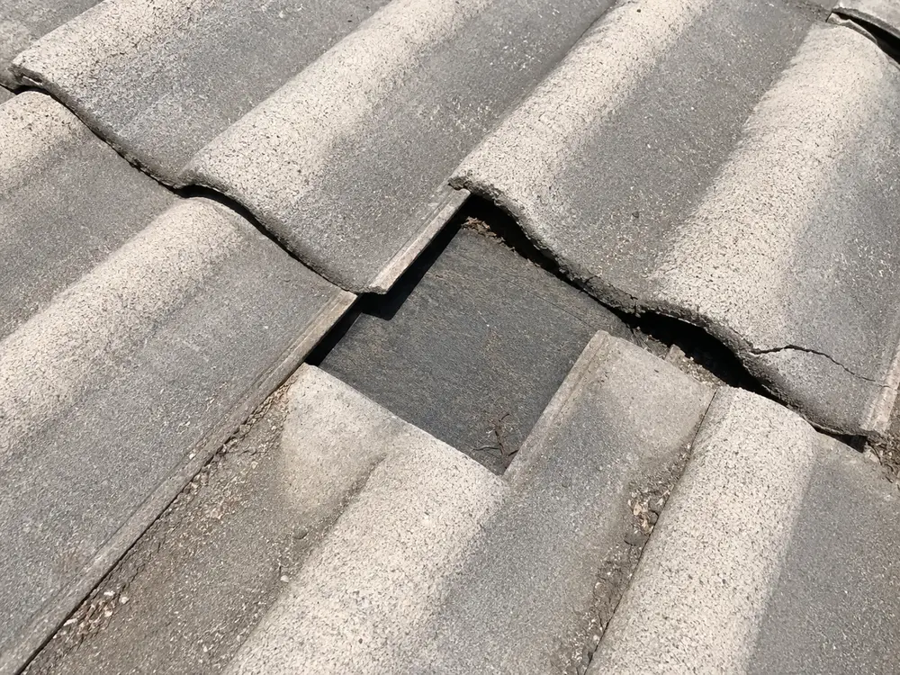 Drone close-up of slipped concrete roof tiles exposing the underlayment beneath, found during a Riverside home inspection