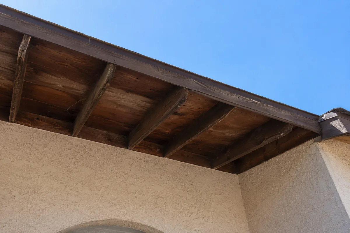 Open eaves with exposed wooden rafter tails on a stucco home, a common ember entry point on older Wildomar properties