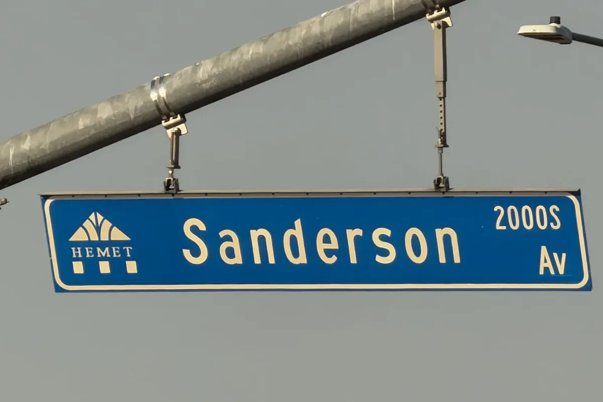 Blue City of Hemet street sign for Sanderson Avenue, 2000 South, with the Hemet city logo, hanging from a signal arm