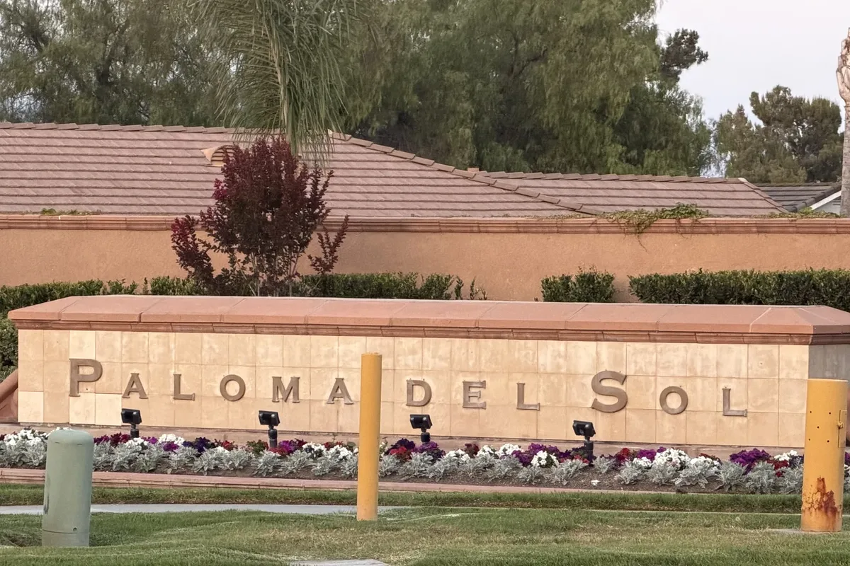 Paloma del Sol community entry monument with stone letters, flower beds and a tile-roofed wall behind it